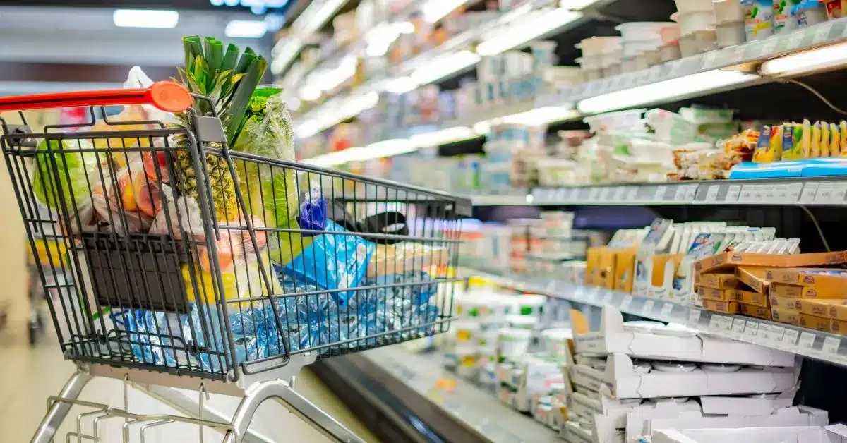 A photo of a full shopping trolley down a supermarket dairy aisle.